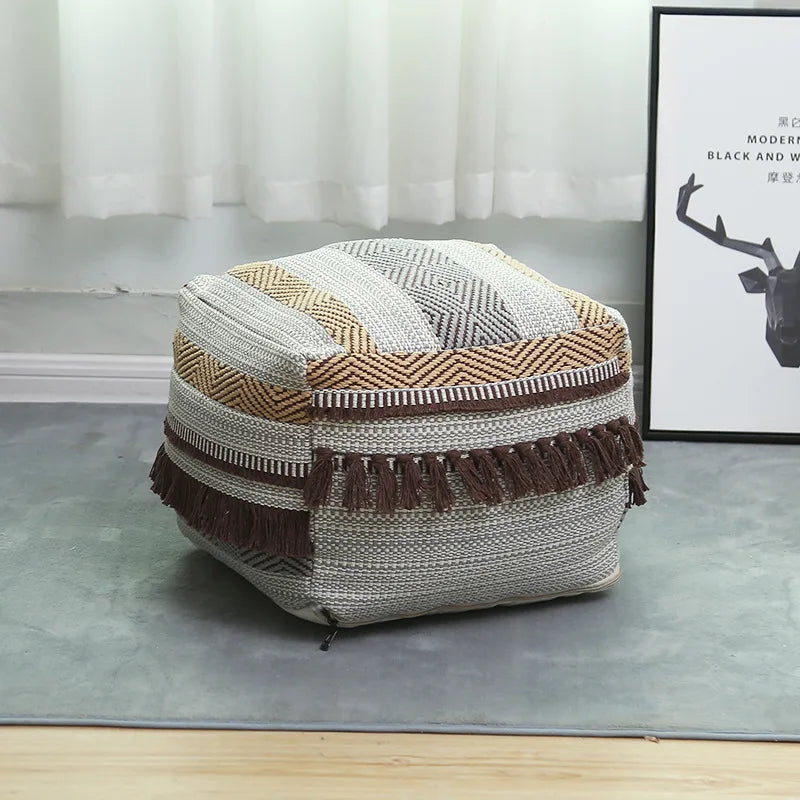Pouf carré beige en tissu texturé placé près d’un canapé