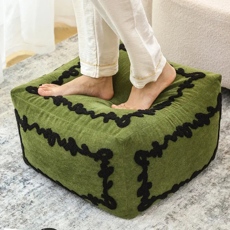 Pouf carré Sésame Sauge utilisé comme repose-pieds dans un intérieur