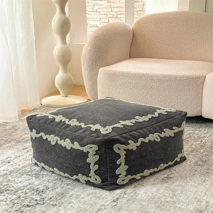 Pouf carré Sésame Nocturne en tissu brodé placé dans un salon moderne